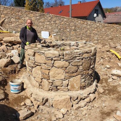 Kamenná studna se zdí v pozadí