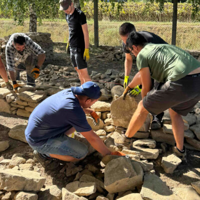 Účastníci kurzu staví suchou kamennou zeď v praxi