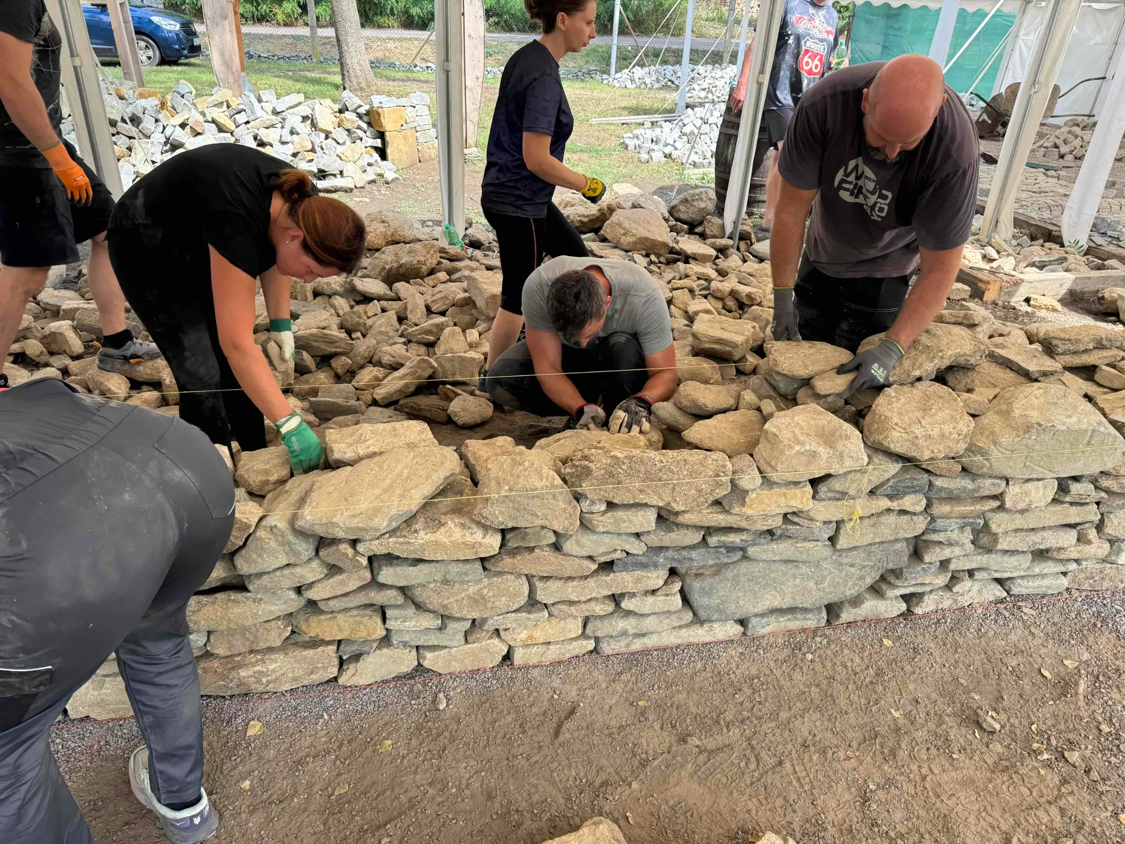 Účastníci staví suchou kamennou zeď v Novosedlech